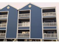 Blue condominium building featuring multi-level balconies, white railings, and elevated parking for a coastal design at 4305 N Ocean Blvd. # 205, North Myrtle Beach, SC 29582
