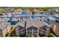 Stunning aerial view of the condo complex overlooking a beautiful marina filled with boats and surrounding buildings at 4609 Lightkeepers Way # 11J, Little River, SC 29566