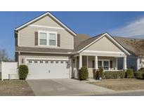 Two-story house with light beige siding, a white garage door, and a covered porch at 5314 Abbey Park Loop, Myrtle Beach, SC 29579