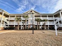 Two-story condo building with palm trees and grassy area at 5801 Oyster Catcher Dr. # 1812, North Myrtle Beach, SC 29582