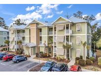 Green three-story building with balconies and parking at 130 Puffin Dr. # 3-E, Pawleys Island, SC 29585