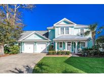 Two-story light teal house with a metal roof, two-car garage, and manicured lawn at 404 Banyan Place, North Myrtle Beach, SC 29582