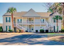 Two-story condo building featuring a palm tree, white railings and green shutters, complemented by parking spots at 5011 Harvest Dr. # 101, Myrtle Beach, SC 29579