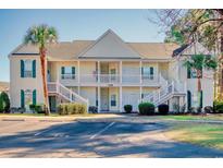 Inviting condo building with a charming white exterior and manicured landscaping and plentiful parking at 5011 Harvest Dr. # 101, Myrtle Beach, SC 29579