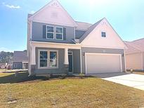 Charming two-story home featuring gray siding, a two-car garage, and a well-manicured lawn at 1212 Nw Calabash Station Blvd., Calabash, NC 28467
