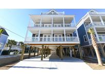 Three-story beach house with white exterior, multiple balconies, and parking underneath at 229 South Waccamaw Dr., Garden City Beach, SC 29576