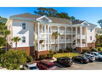 Three-story building with light pink exterior, balconies, and ample parking at 4141 Hibiscus Dr. # 102, Little River, SC 29566