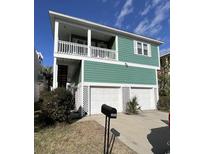 Two-story home featuring a green exterior, a white balcony, and a two-car garage with white doors at 4714 Woodland St., North Myrtle Beach, SC 29582