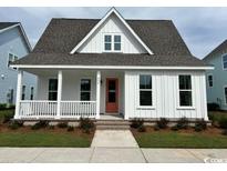 Charming single-Gathering home featuring a cozy front porch, a well-manicured lawn, and an orange front door at 540 Ayrhill Loop, Myrtle Beach, SC 29588