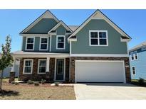 Two-story home featuring teal siding, stone accents, a two-car garage, and a well-manicured lawn at 578 Haven View Way, Murrells Inlet, SC 29576
