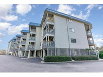 Gray building with blue roof, multiple balconies, and parking underneath at 6000 N Ocean Blvd. # 205, North Myrtle Beach, SC 29582