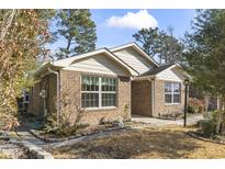 Charming brick home with manicured landscaping and mature trees on a sunny day at 461 Spauldingwood Rd., Little River, SC 29566