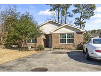 Charming brick home featuring a well-maintained lawn, mature trees, and a private driveway at 461 Spauldingwood Rd., Little River, SC 29566