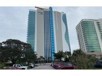 Oceans One resort condo building with parking area, trees, and the building is the focal point at 107 S Ocean Blvd. # 707, Myrtle Beach, SC 29572