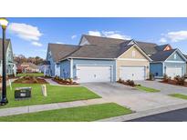 Charming townhomes feature attached garages, manicured lawns, and inviting curb appeal on a sunny day at 2602 Blue Crane Circle # 101, Myrtle Beach, SC 29577