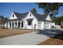 Charming white farmhouse with a gray roof, spacious driveway, and an attached two-car garage at 261 Marsh Tacky Loop, Myrtle Beach, SC 29588