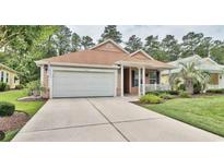 Charming single-story home featuring a two-car garage, well-manicured landscaping, and a welcoming front porch at 414 Grand Cypress Way, Murrells Inlet, SC 29576