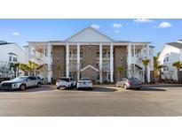 Three-story condo complex showing brick facade, white pillars and staircases on a sunny day at 136 Birch N Coppice Dr. # 11, Surfside Beach, SC 29575