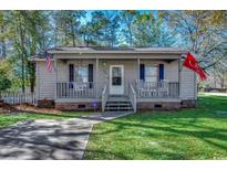 Gray house with a porch, rocking chairs, and American flags at 1500 Docksider Ct., Surfside Beach, SC 29575