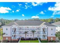 Three-story condo building featuring private outdoor porches, palm trees, and landscaped entryway at 4142 Hibiscus Dr. # 101, Little River, SC 29566