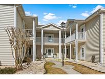 Inviting two-story condo featuring white columns, a covered balcony, and professionally landscaped grounds at 6208 Sweetwater Blvd. # 6208, Murrells Inlet, SC 29576