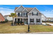 Charming two-story home with gray siding, black shutters, a palm tree, and a well-manicured lawn at 931 Desert Wheatgrass Dr., Myrtle Beach, SC 29579