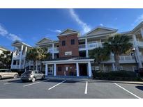 Three-story condo building with brick accents, multiple balconies, and palm trees in front at 1004 Ray Costin Way # 206, Murrells Inlet, SC 29576