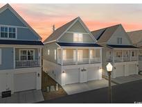 Inviting two-story beach home with a covered porch and ground-level garage at sunset at 129 Marblehead Dr., Little River, SC 29566