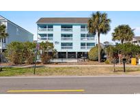 Bright, three-story beach condo with multiple balconies, palm trees, and a black metal fence at 1510 S Ocean Blvd. # 101, Surfside Beach, SC 29575