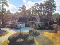 Beautiful brick home featuring a large, well-manicured front yard with mature trees and a spacious driveway at 165 Greenbriar Ave., Pawleys Island, SC 29585