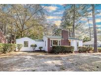 Charming home featuring white siding, brick chimney, green metal roof, and mature landscaping at 2505 Redwood St., Georgetown, SC 29440