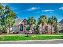 Charming brick home featuring a manicured lawn, mature palms, and classic architectural details at 2803 Ships Wheel Dr., North Myrtle Beach, SC 29582