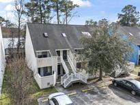 Condo exterior featuring a white staircase, neutral siding, dark roof, and mature landscaping at 416 Cambridge Circle # H5, Murrells Inlet, SC 29576
