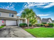 Charming home exterior with well-manicured lawn and landscaping, complemented by a stone facade and a white garage door at 4225 Rivergate Ln., Little River, SC 29566