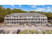 Three-story condo building with a large parking area surrounded by green trees and landscaped grounds at 4506 W Harbour Ct. # U2, Little River, SC 29566