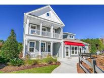 Charming two-story home with a double porch, manicured landscaping, and a bright red awning at 2505 Brescia St., Myrtle Beach, SC 29579
