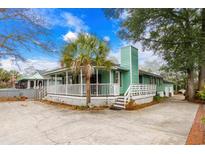 Charming green home with a white picket fence and a lush palm tree in the front yard at 5520 N Kings Hwy., Myrtle Beach, SC 29577