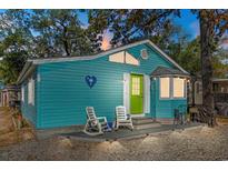 Charming blue cottage featuring a vibrant green door and a cozy front porch with rocking chairs at 6001 - N75 S Kings Hwy., Myrtle Beach, SC 29575