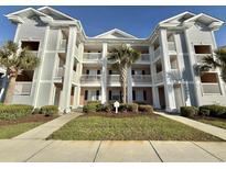 Inviting condo exterior with multiple balconies, lush landscaping, and a central palm tree at 635 Waterway Village Blvd. # 12-I, Myrtle Beach, SC 29579