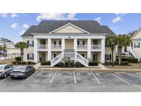 Inviting condo exterior showcasing large columns and a double staircase entry with ample parking spaces at 805 Sunswept Ct. # 102, Murrells Inlet, SC 29576