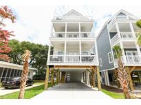 Charming elevated beach house featuring a white exterior, multiple decks and ample parking at 114-B 7Th Ave. N, Surfside Beach, SC 29575