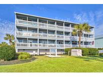 Four-story condo building with white railings and palm trees on a sunny day at 1210 N Ocean Blvd. # 202, Surfside Beach, SC 29575