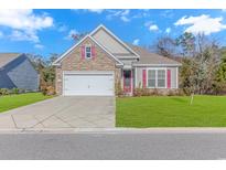 Charming single-Gathering home featuring stone accents, red shutters, two-car garage, and a well-manicured lawn at 124 Castaway Key Dr., Pawleys Island, SC 29585