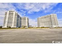 Beachfront condominium complex featuring multiple high-rise towers and stunning ocean views against a partly cloudy sky at 161 Seawatch Dr. # 1101, Myrtle Beach, SC 29572