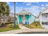 Charming beach cottage with a cozy front porch and vibrant turquoise siding and walkway at 230 Addison Cottage Way, Murrells Inlet, SC 29576