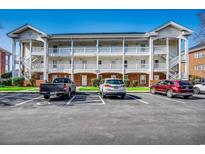 Bright condo with a white facade, brick accents, and parking lot at 3923 Gladiola Ct. # 204, Myrtle Beach, SC 29588