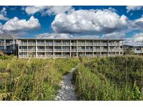 Beautiful beachside condo building with white balconies overlooking a sandy path and lush dunes at 4406 N Ocean Blvd. # A-1, North Myrtle Beach, SC 29582