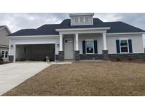 Charming single-story home with stone accents, an attached garage, and a well-maintained lawn at 994 Oak Hollow St., Longs, SC 29568