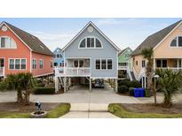 Charming raised beach home featuring colorful exteriors and well-maintained landscaping at 1031 N Dogwood Dr., Surfside Beach, SC 29575