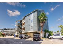 Attractive condo building featuring wood siding, covered parking, and a mature palm tree at 1101 Possum Trot Rd. # A-101, North Myrtle Beach, SC 29582